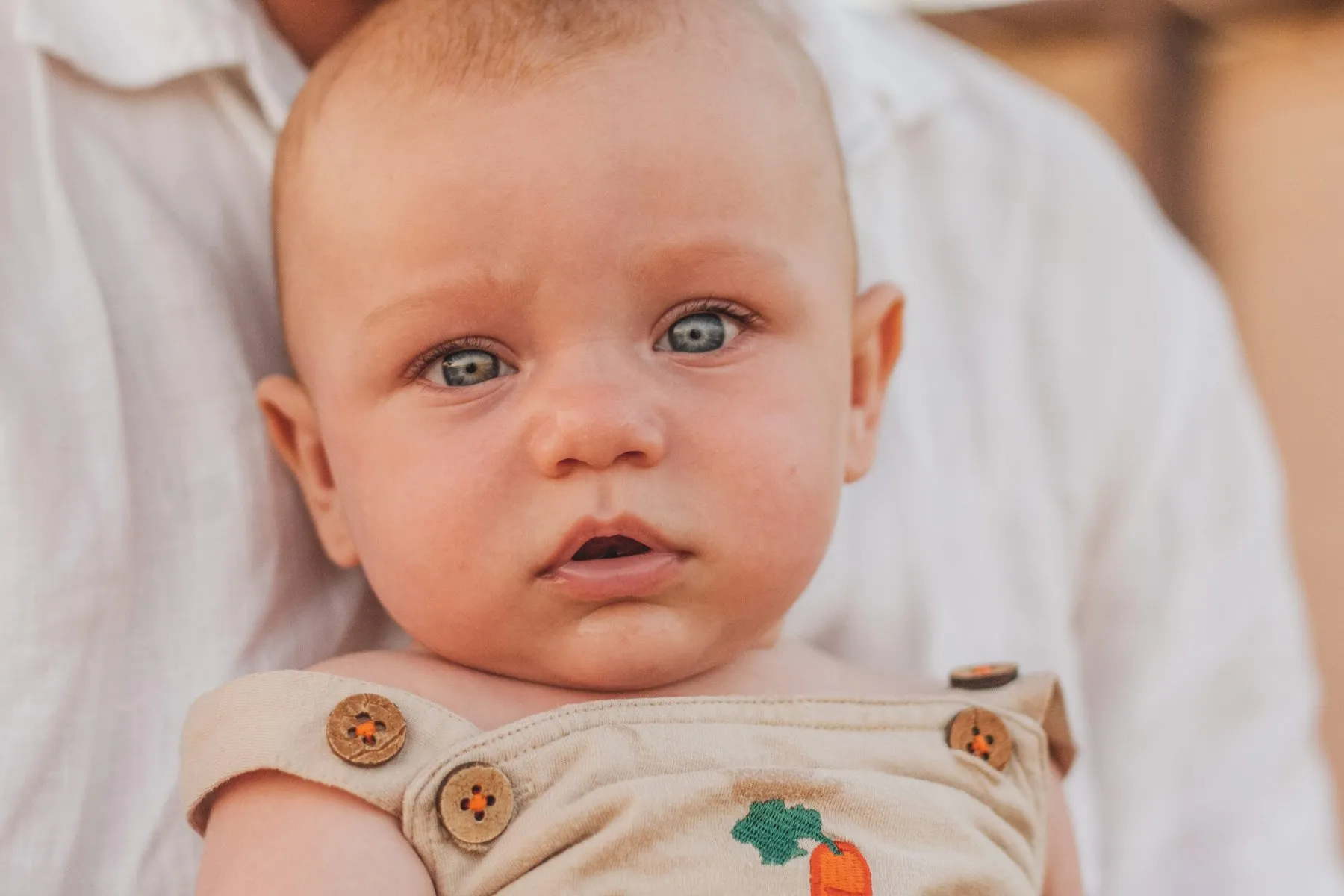 Baby-Porträt mit großen blauen Augen auf dem Arm der Mutter