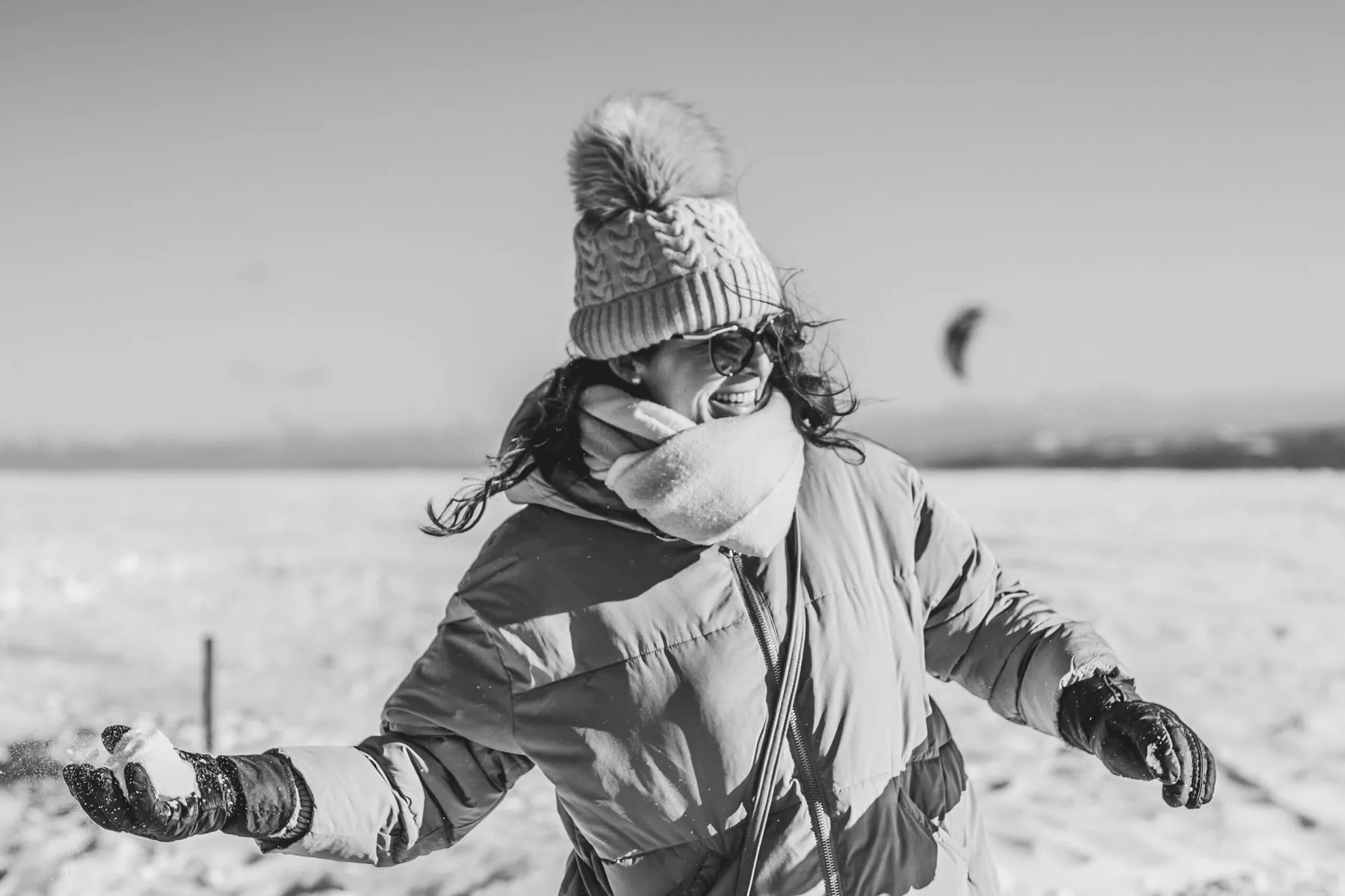 Lachende Frau mit Schneeball im Winter, Schwarz-Weiß-Aufnahme